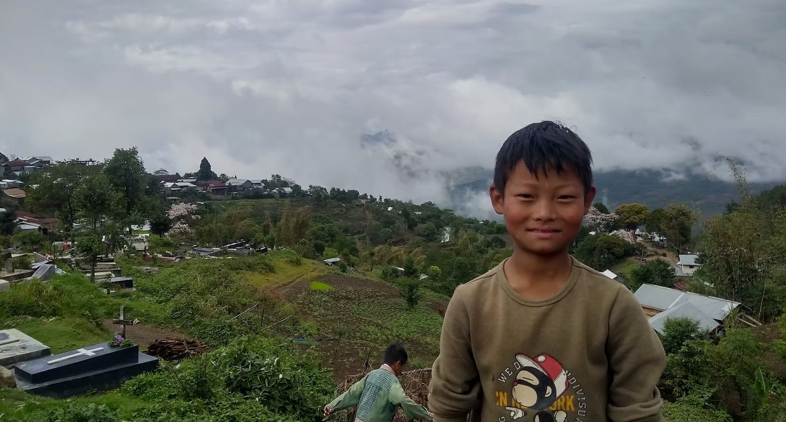 A boy smiling on a green hillside in Ukhrul, Manipur